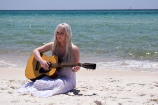 浜辺で優雅にギターを弾く美女